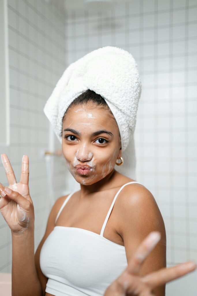 happy girl in bathroom showing peace sign while doing skincare